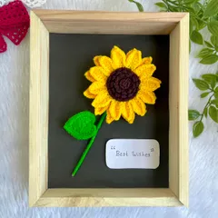 A single, large crochet sunflower beautifully displayed in a wooden frame with a "Best Wishes" note. It makes for a thoughtful and unique gift.