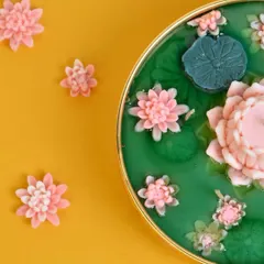 A close-up of the intricate details on our Lotus Pond Urli candle. The hand-poured lotus and water lilies float in a serene pool of gel wax, bringing a sense of tranquility to any room.