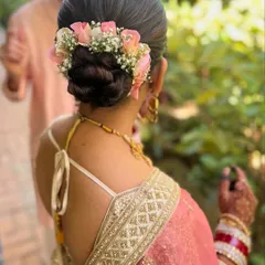 A beautiful braided bun adorned with fresh pink roses and baby's breath. This is a romantic and elegant hairstyle for a wedding or reception.