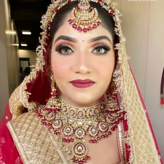 Mastering the classic Indian bridal look is a cornerstone of our curriculum. Here, our student has created a flawless, radiant base with bold maroon lips and defined eyes, complemented by traditional red and gold jewelry, a look that is always in demand.