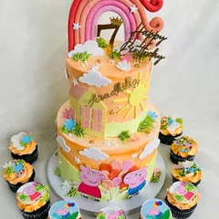 A sunny Peppa Pig themed cake for a 7th birthday celebration. This two-tier cake is decorated with a house, sun, and a rainbow, surrounded by cupcakes featuring the beloved characters.