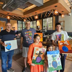A happy group of all ages proudly displaying their finished vase paintings. Our workshops are designed to be fun for everyone, from young children to grandparents.