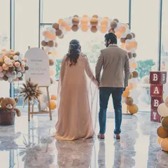 A 'We Can Bearly Wait' themed baby shower. This shot captures the parents-to-be standing before a custom balloon arch, ready to welcome their new arrival.