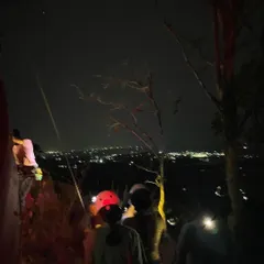 A stunning view of our climbers on the rock at night, illuminated by headlamps against the city lights below. Our full moon climbing sessions are a truly magical experience.