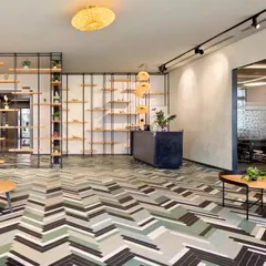 A minimalist and modern reception area designed for a flexible workspace. The geometric flooring, clean lines, and open shelving create a welcoming and organized entry point, setting a tone of efficiency and contemporary style.