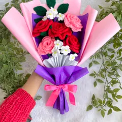 A beautiful and bright bouquet featuring a mix of red and pink crochet roses with small white flowers. The vibrant pink and purple wrapping makes the colors pop, creating a perfect gift for someone dear.