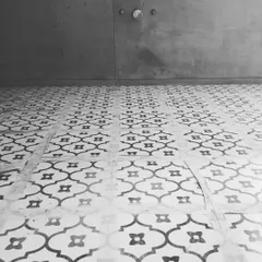 We love the timeless elegance of this black and white patterned tile floor. The classic quatrefoil design adds a touch of sophistication and visual rhythm to the space, contrasting beautifully with the modern, minimalist concrete wall.