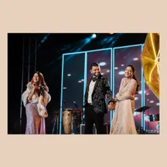 A candid moment on the Sangeet stage, capturing the couple's happy interaction with a performer.