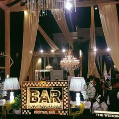 A wide shot of our bar setup in a beautifully draped wedding marquee, showing how our lighting and decor integrate seamlessly with the overall event design.