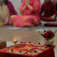 The altar is prepared for puja, with a lit diya, flowers, and a swastika drawn with rice. These symbols create a sacred atmosphere for our spiritual practices.