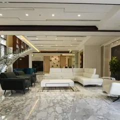 Luxury and spaciousness are defined by a cohesive design language. This living area features pristine marble floors, a crisp white sectional sofa, and recessed lighting, creating a sophisticated environment that feels both grand and inviting.