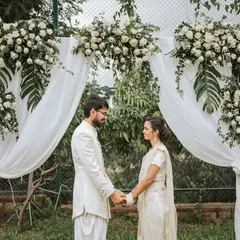 A couple stands hand-in-hand under a beautiful floral arch, a perfect setting for a destination wedding.