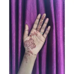 A delicate design featuring three small roses on the palm, with a light vine extending up the wrist and finger.
