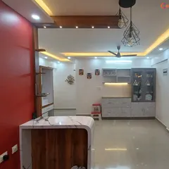 An open-plan living and kitchen area unified by a sophisticated false ceiling with perimeter cove lighting. This technique makes the space feel larger and brighter, highlighting the room's architecture.