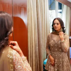 A full-length view of this soft glam look. The makeup is natural and radiant, perfectly complementing her elegant beige outfit for a wedding guest appearance.