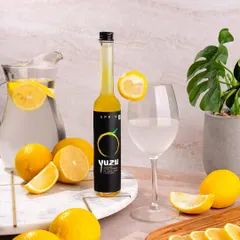 Showcasing Sprig's Yuzu Citrus Extract in a bright and refreshing setting. Surrounded by fresh lemons and a pitcher of water, this image communicates the product's natural flavor and its use in creating delicious drinks.