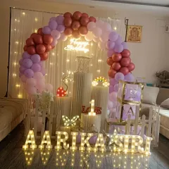 For this first birthday, I created a beautiful backdrop using a full balloon arch against a curtain of fairy lights. The design includes marquee letters and number, 'BABY' blocks, and other small props for a complete look.