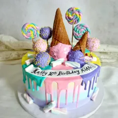 Another fun take on a Candyland theme, this cake uses a rainbow of pastel colors in a drip effect. It's topped with ice cream cones, lollipops, and cake pops for a playful and delicious tenth birthday celebration.