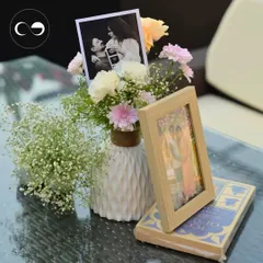 A beautiful tabletop arrangement from the storybook shower, featuring a vase of flowers, a sonogram picture, and a framed photo of the couple, all resting on a stack of books to tie into the theme.