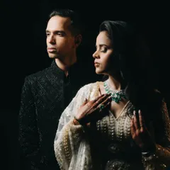 A dramatic, low-key portrait from an engagement ceremony. The focused lighting highlights the couple's elegant attire and serene expressions, creating a timeless, artistic photograph.