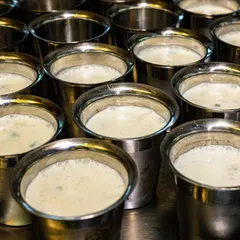 Rows of traditional steel glasses filled with buttermilk for an Onam sadhya. This image captures a cultural detail that tells the story of the special event at Kari Apla.