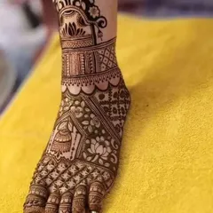 A close-up of a single foot, showcasing the intricate details of the design. It features a hanging jhumki motif and delicate floral patterns.