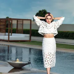 An editorial shot of actress Ragini Dwivedi for a magazine cover. The poolside location and the unique white cutout dress create a majestic and high-fashion look.