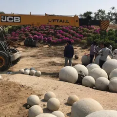 The installation process for the stone spheres at our Hyderabad site. This behind-the-scenes look shows the scale of the project, with a JCB crane and a large team at work.
