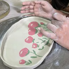 Here I am painting a floral design onto a hand-built platter. I often use my fingers to blend the colors, which gives the piece a soft, painterly quality.