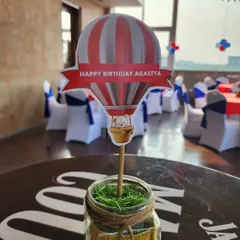 Another style of table centerpiece for the hot air balloon party. This one features a personalized cutout with a teddy bear peeking out of the balloon basket, adding a playful touch.