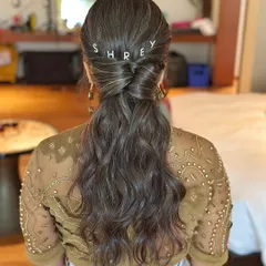 A fun and personalized touch for a carnival-themed party in Goa. I styled this textured low ponytail and added custom clips spelling out the client's name, "SHREY". It's a playful detail that makes the hairstyle unique.