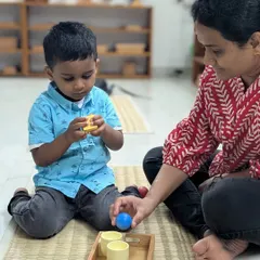 A child explores the texture and shape of different objects with his mother nearby. This gentle introduction to our sensory materials is guided by curiosity and supported by a trusted adult.