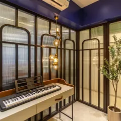 A creative and musical workspace. This room features a keyboard set up against a backdrop of elegant fluted glass and wood panels, with a bold blue wall adding a splash of color.