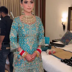 A full-length view of the bride in her beautiful turquoise sharara. The makeup perfectly complements the unique color of her outfit.