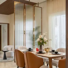 A modern dining setup designed for both style and comfort. We used a fluted glass and brass partition to create a sense of separation without closing off the space, complemented by tan leather chairs and a marble-topped table for an elegant dining experience.