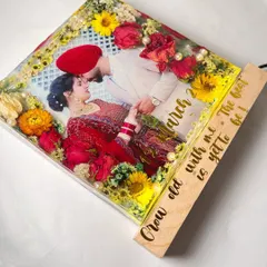 This square block art is a bestseller. It features a couple's photo surrounded by brightly colored preserved flowers, with a custom quote engraved on the wooden stand.