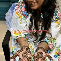 A happy client showing her beautiful and simple festive mehndi. The design features lotus mandalas on the palms with leafy patterns on the fingers.