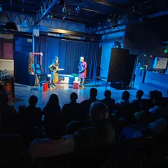 A wide shot of a student production, showing the audience engrossed in the performance within our intimate black box setting.