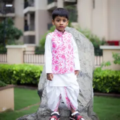 A classic portrait of a young boy in a stylish pink and white traditional outfit. We take posed shots that are perfect for framing.