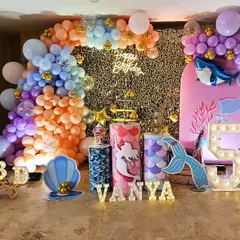 A magical mermaid-themed 5th birthday party for Vanya. The decor is filled with details like a sequin backdrop, character cutouts of Ariel, balloon arrangements in ocean colors, and light-up letters, creating an enchanting underwater world.