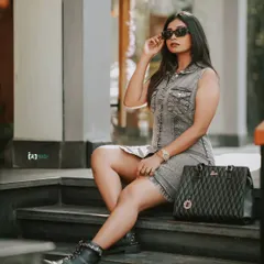 Street style at its best. This shot captures a full look, from the denim dress and combat boots to the sunglasses and handbag, against a simple urban backdrop.
