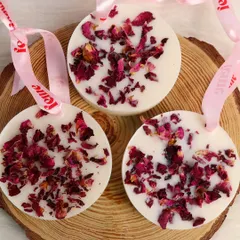 Our wax sachets with dried rose petals, displayed on a natural wood slice.