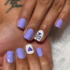 Simple, sweet, and full of heart. This design uses a soft lilac polish with two white accent nails featuring a tiny heart and a delicate plant motif, perfect for a subtle and charming look.
