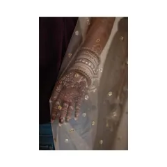 A beautiful detail shot of the bride's mehendi-adorned hand, seen through the sheer fabric of her dupatta.