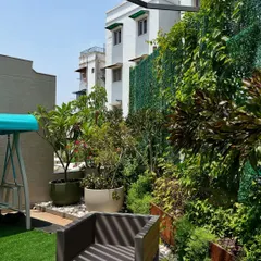 This terrace includes multiple zones for relaxation, including a swing and comfortable seating. The vertical green mesh provides privacy from neighboring buildings while allowing light and air to filter through.