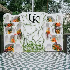 The main photo backdrop for the 'Citrus Safari' event, featuring a custom monogram, organic wall niches, and sprawling ivy on a patterned floor.