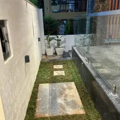 A narrow side yard transformed with a simple lawn and stone pavers. This practical and elegant solution creates a functional walkway while still incorporating a touch of green.