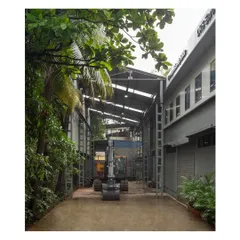 The covered breezeway designed for the movement of heavy machinery between the workshop and outdoor areas. The tall steel structure and translucent roofing create a functional and well-lit transitional space.