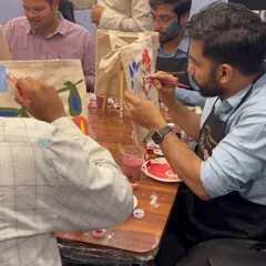 A participant fully engaged in painting his tote bag during our Holi-themed workshop with Houlihan Lokey. The abstract floral design is coming along beautifully.
