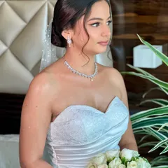A side profile of Beracah, showcasing her elegant updo and the flawless finish of her makeup. The look was designed to be picture-perfect from every angle.
